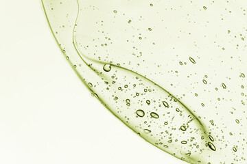 Gel serum texture. Green cosmetic liquid oil cream background. Transparent skincare product with bubbles splash closeup