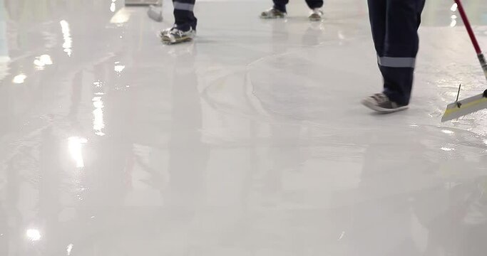 A team of builders makes heavy Duty Industrial Floor Coatings. A team of professionals makes a polymer floor in a factory workshop.