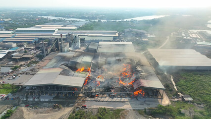 From above, witness the aftermath of industrial catastrophe. Flames rage, devouring a collapsed...