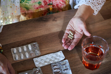 A close up of a hand of senior woman with pills and blister packs.