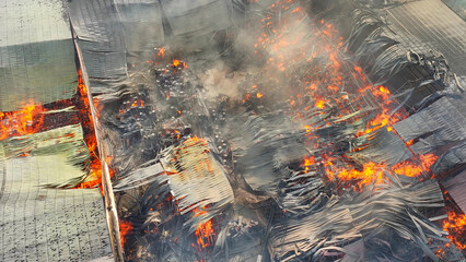 An aerial perspective unveils a scene of catastrophe: an industrial plant consumed by fire. Flames...