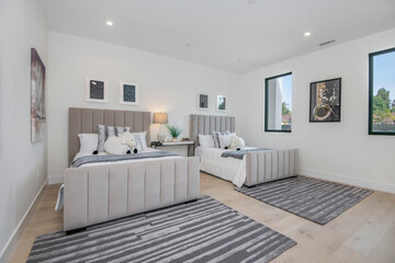 Two neatly made beds in a white bedroom in a modern new construction home in Los Angeles