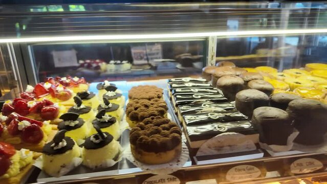 4k video footage of Various types of bread on display in a bakery or pastry such as macarons, croissants and danish. Modern bakery with different kinds of Loaf, bread, cakes and buns.