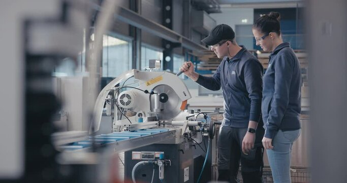 Technician explaining metal sawing machine to colleague