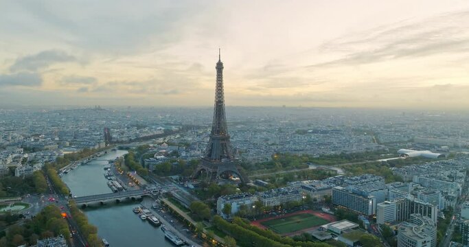 Beautiful view of famous Eiffel Tower in France with magical morning cloud and fog. Wide establishing aerial drone fly over seine river in paris city center, best travel destination landmark in Europe