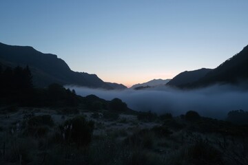 Explore the mystical atmosphere of dawn in a mist-shrouded valley, with mountains looming in the distance and the promise of a new day, Generative AI