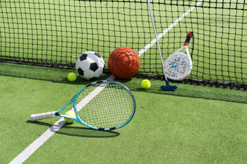 A variety of sports equipment including an american football, a soccer ball, a tennis racket, a...
