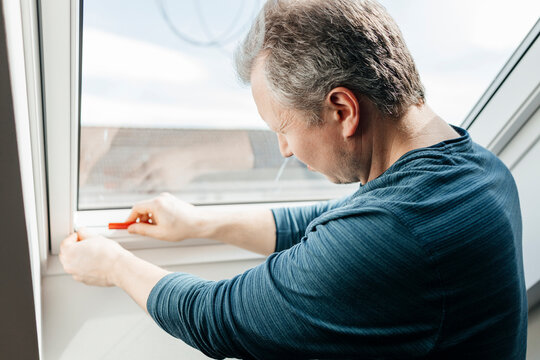 Man installing blinds on window at home