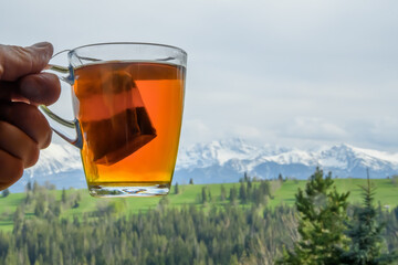 Górska herbata rozgrzewająca w przezroczystej szklance, w rozmytym tle góry Tatry