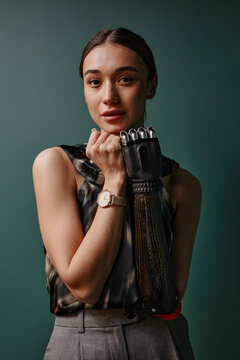 Confident woman with black bionic hand standing in front of green wall