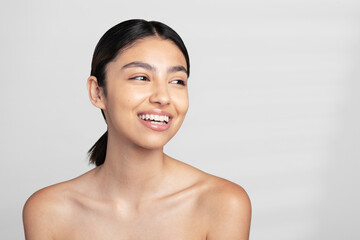 Happy beautiful young shirtless woman looking away against white background