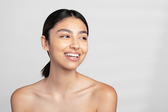 Happy beautiful young shirtless woman looking away against white background