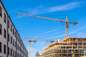 Germany, Bavaria, Munich, Industrial cranes looming over construction site