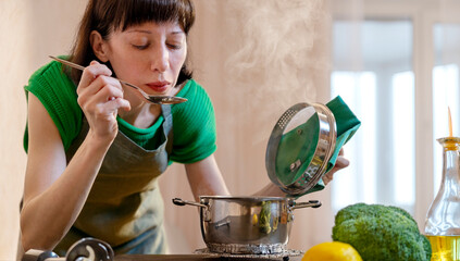 Woman tasting food with spoon in kitchen at home