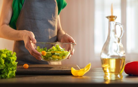 Woman tossing salad in bowl at home