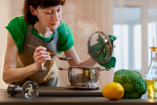 Woman checking food in cooking pan at home