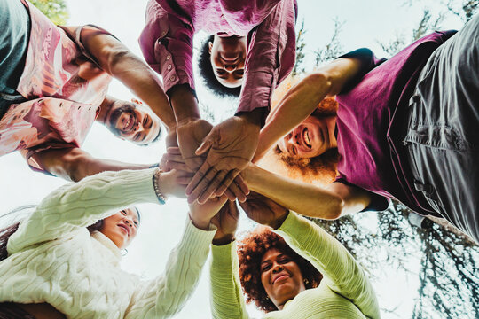 Multiracial friends stacking hands at park