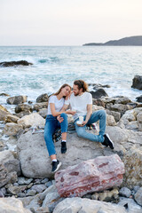 Two Women Sitting on Rocks by the Ocean