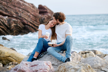 Man and Woman Sitting on Rocks by Ocean