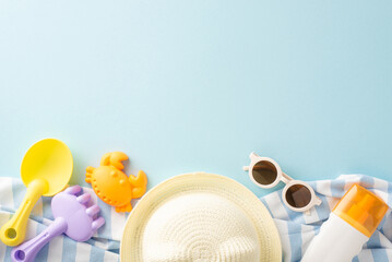 A collection of colorful children's beach toys, sunglasses, sunscreen, and a straw hat laid out on...