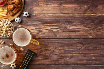 An inviting display of game day essentials with beer, fried chicken, french fries, peanuts, and a remote control on a rustic wooden table