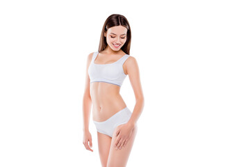 Fototapeta premium Portrait of thin sportive woman with perfect body in white cotton underwear bikini isolated over white background touching hips enjoying smooth ideal leg's skin