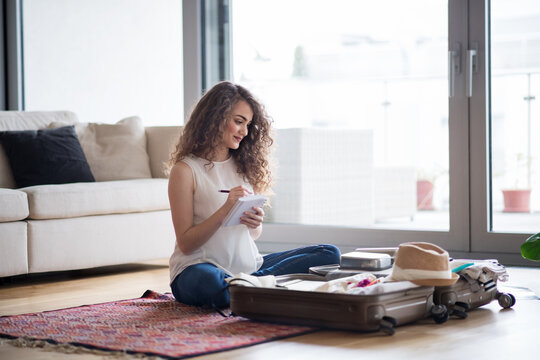 Beautiful woman planning summer vacation abroad, packing suitcase. Solo traveller preparing for trip.