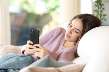 Relaxed woman on a couch checking cell phone