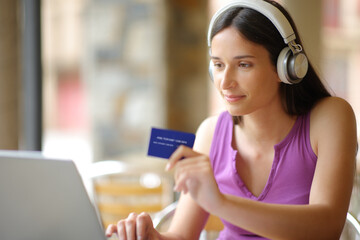Woman buying online with laptop wearing headphone