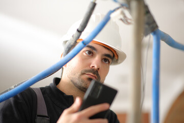 Electrician checking installation using phone