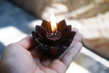 The light on a lotus pray candle held by a hand