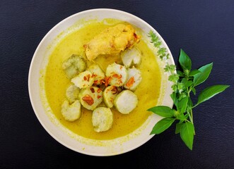Opor ayam lontong on black background. A typical Indonesian dish made from coconut milk , turmeric,...