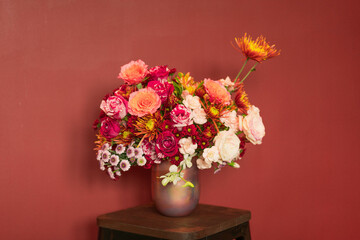 bouquet of flowers in vase behinds red background
