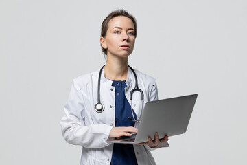 Portrait of a successful doctor with an open laptop who is typing a treatment recommendation