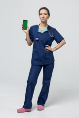 The surgeon is holding a smartphone with a green screen. Doctor on a white background