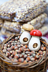 Close-up of hazelnuts in rustic wicker basket, accompanied by whimsical nutcrackers shaped like mushrooms, ideal for culinary and seasonal themes. Selective focus, defocus. Vertical