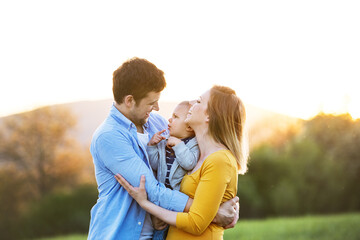 Fototapeta premium New parents holding small toddler, baby, outdoors in spring nature. Happy family moment
