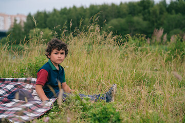 Description: Curly-haired young boy explores lush green fields during summer, enjoying outdoor...