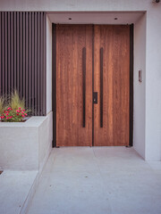 A modern design house entrance with a wooden door, black fence and colorful flowers. Travel to Athens, Greece.