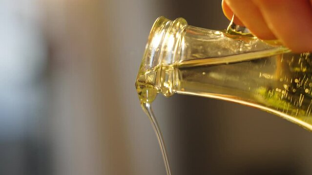 sunflower or olive oil is poured into a frying pan or into a salad for cooking in slow motion close-up