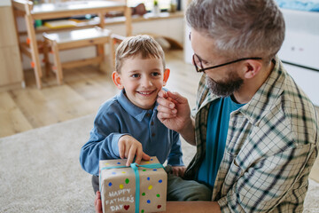 Dad get a handmade gift from little son, present wrapped in diy homemade wrapping paper. Happy...