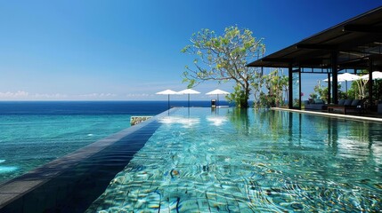 infinity pool merging with ocean horizon, framed by a tall tree and clear blue sky, with a white umbrella providing shade