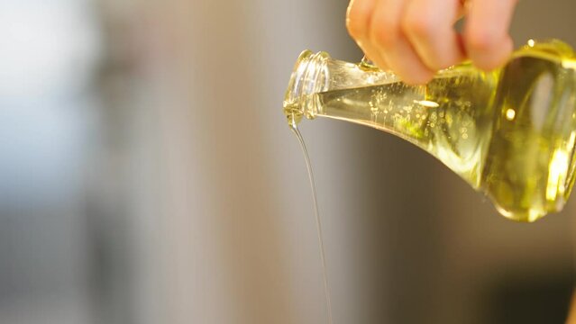 sunflower or olive oil is poured into a frying pan or into a salad for cooking in slow motion close-up