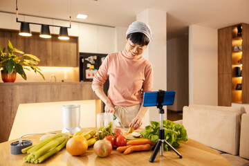 A happy japanese middle-aged woman making healthy meal and live streaming on phone. - Powered by Adobe