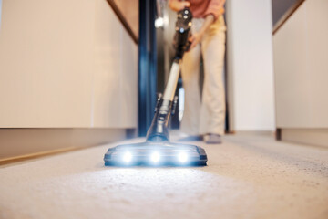 Close up of a vacuum cleaner vacuuming carpet at home.