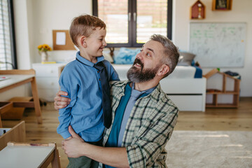 Portrait of dad hugging little son, ties around neck. Teaching how to tie a tie. Happy Fathers day...