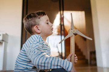 Boy holding wind turbine model. Concpet of renewable energy sustainable lifestyle for next...