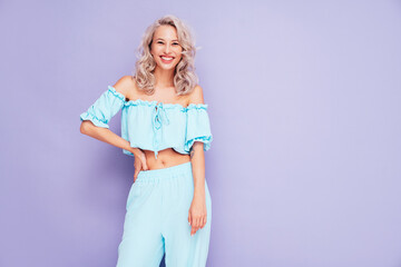 Young beautiful smiling female in trendy summer blue costume clothes. Carefree blond woman posing...