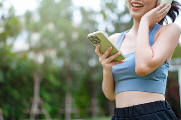 fit, fitness, exercise, run, runner, sports, jogging, jogger, health, training. A woman is holding a smartphone in her hand while wearing a blue tank top and black pants.