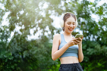 youth, reading, typing, chat, outside, outdoors, happy, smiling, social, message. A woman is smiling and holding a cell phone. She is wearing headphones and she is listening to music.